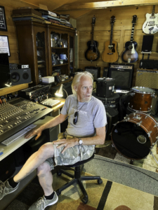 Dave Tann sitting in front of a soundboard in a recording studio.